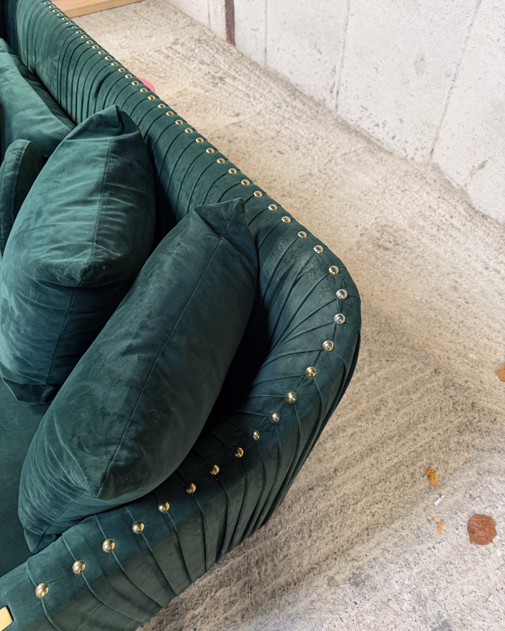 Dark Green Velvet Sofa – Deep green velvet sofa with gold base detailing.